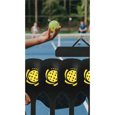 Person holding a pickleball on a court with pickleball stands in the foreground