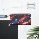 A zip-around wallet with a red, blue, and black galaxy print, styled in a flat-lay composition on a white marble background with fitness props including a dumbbell, a water bottle, a yoga mat, and a palm leaf.