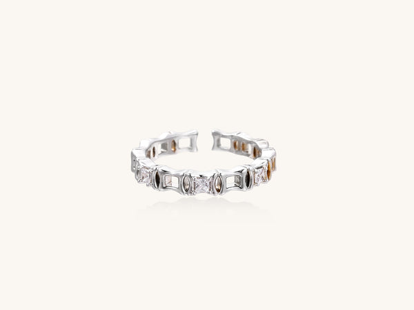 Close-up of geometric gold-plated ring with alternating rectangular blocks and zirconia crystals on white background.