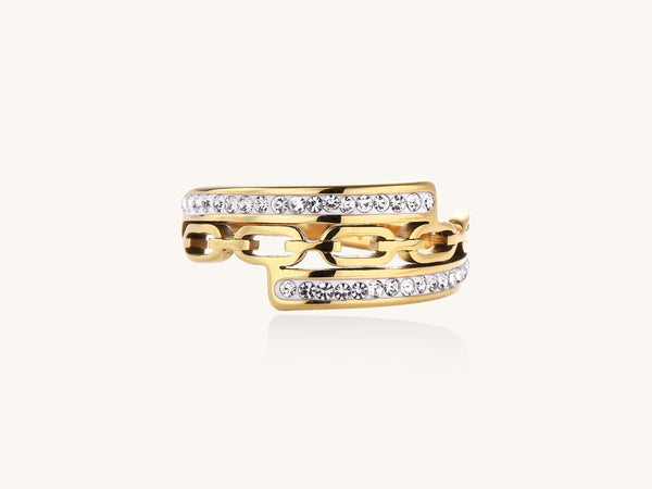 Gold-plated chain-link ring with rhinestone rows on cream background, showing bold geometric design and sparkling details.
