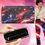 A zip-around wallet with a galaxy print in red, blue, and black is shown in a collage-style product image. The top half shows the closed wallet against a pink gradient background, the bottom left shows hands holding the open wallet to display the interior, and the right side shows a woman wearing matching galaxy-print leggings.
