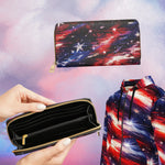 A zip-around wallet and matching zip hoodie featuring a red, white, and blue galaxy star pattern, shown against a pink and blue cosmic background. One hand is holding the open wallet to show the interior, and the matching hoodie is partially visible on the right.