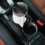 Car cup holder with a white mug featuring black star patterns, placed inside a vehicle.