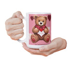 Mug with a teddy bear design held by a hand on a white background