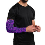 Person wearing a black shirt with a purple glittery arm sleeve on a white background