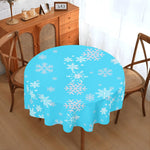 Round table with a blue tablecloth featuring white snowflakes in a dining room setting.