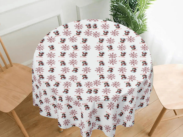 Round table with a decorative tablecloth featuring snowmen and snowflakes on a white background.