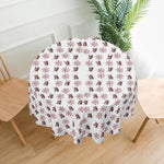 Round table with a decorative tablecloth featuring snowmen and snowflakes on a white background.