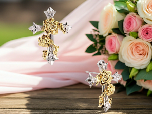 Gold and silver floral earrings on a wooden surface with pink and white roses in the background.