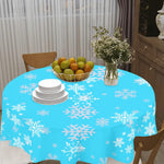 Table with a blue snowflake patterned tablecloth, fruit bowl, and vase.