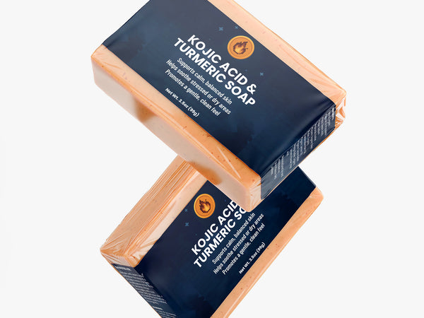 Two bars of Kojic Acid Turmeric Soap on a white background
