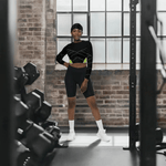Black Neon Grid Long Sleeve Crop Top - Woman standing in gym with weights | Our Phoenix Rise