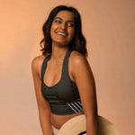 Model smiling in black high impact longline sports bra, holding a straw hat | Our Phoenix Rise