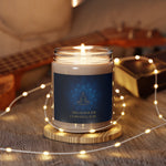 Candle in a jar with a blue label featuring a meditation design, surrounded by string lights on a textured surface.